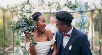 a bride and groom smile at each other while walking back up the aisle