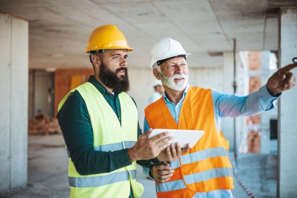 two construction workers look over a project plan on a tablet